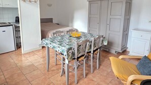 Een kleine keuken met een eettafel, stoelen, een bed en een kledingkast.