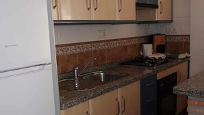 Une cuisine équipée d’un évier, d’une cuisinière et de placards.