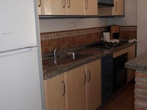 A kitchen with a sink, stove, and cabinets. - Bright seaside apartment in Almuñécar (Almuñécar)