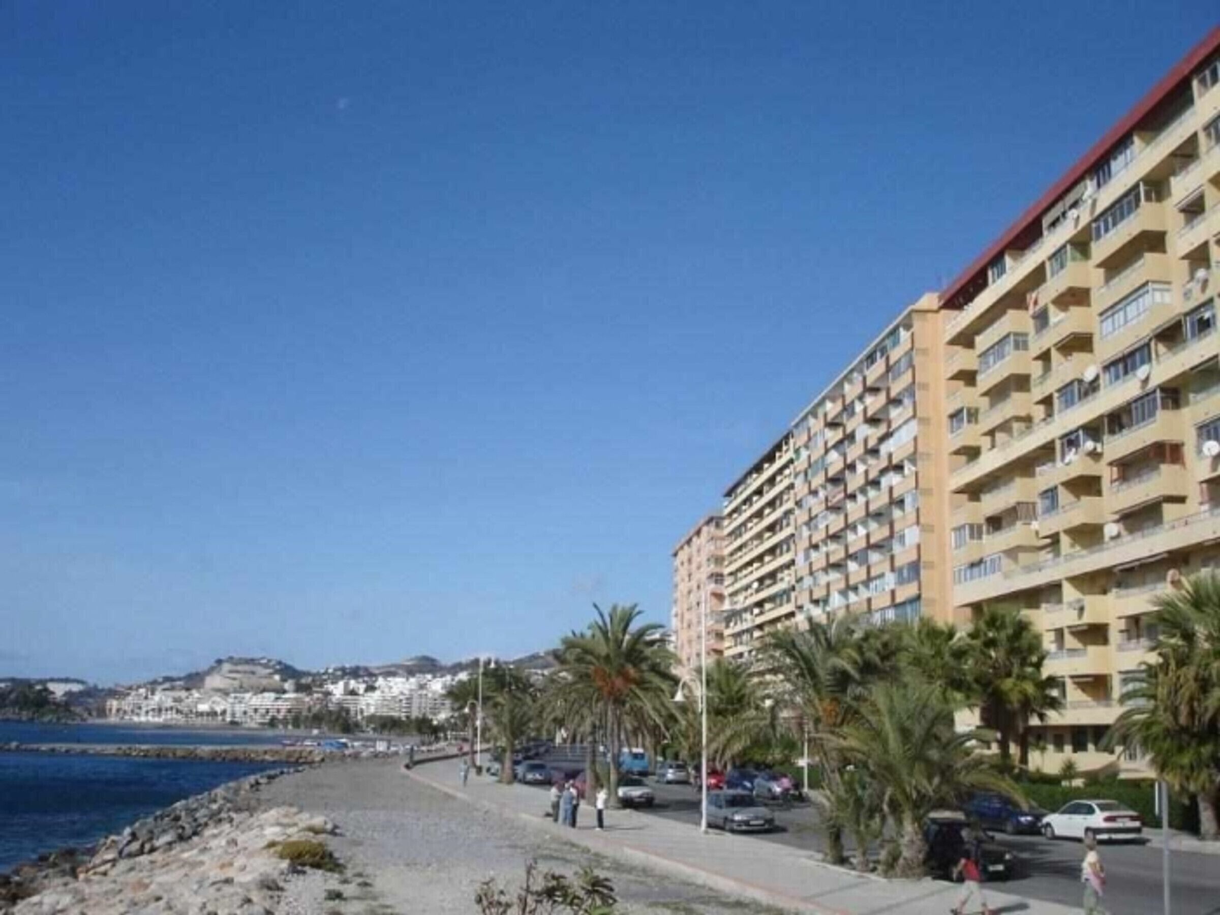 Ett hotell vid kusten med flera balkonger, en sandstrand och en klarblå himmel.