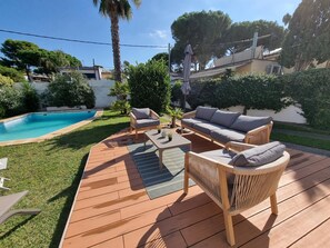 A backyard with a swimming pool, wooden deck, outdoor furniture, and lush greenery. - House in L'Escala with private pool and air conditioning, near beach (L'Escala)