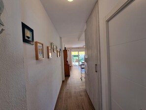 A hallway with framed pictures on the wall, a wooden floor, and a door on the right. - Apartment with terrace 400m from Riells beach (L'Escala)