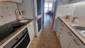 Een keuken met witte kasten, een granieten aanrechtblad, een koffiezetapparaat en uitzicht op een eetgedeelte.