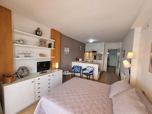 A bedroom with a bed, a TV, a desk, and a chair. There is a kitchenette in the background. - Studio with Terrace Near Beach in L'Escala (L'Escala)