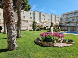 Ein Hotelinnenhof mit Swimmingpool, einer Statue und einem gepflegten Rasen.