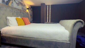 Een moderne slaapkamer met een groot bed, een hoofdbord met een marmerachtig patroon en een wandlamp.