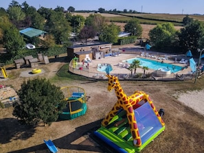 A fenced outdoor area with a pool, inflatable play structures, and a slide. - Accessible Chalet with Terrace – 2 Bedrooms in Naucelle (Naucelle)