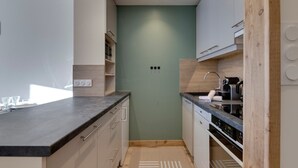 A modern kitchen with white cabinets, a black countertop, and a wooden backsplash. - 45m² Duplex for 4, ski-in ski-out in Tignes Val Claret (Tignes)