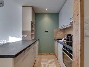 A modern kitchen with white cabinets, a black countertop, and a wooden backsplash. - 45m² Duplex for 4, ski-in ski-out in Tignes Val Claret (Tignes)