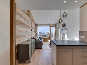 A modern kitchen with a wooden accent wall, a built-in bench, and pendant lighting. - 45m² Duplex for 4, ski-in ski-out in Tignes Val Claret (Tignes)