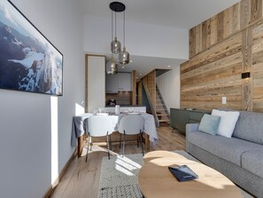 A modern living space with a dining area, a sofa, and a staircase. - 45m² Duplex for 4, ski-in ski-out in Tignes Val Claret (Tignes)
