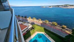 A hotel with a pool, a view of the sea, and a road with a pedestrian crossing. - Apartment in L'Escala near the beach, 2 bedrooms (L'Escala)