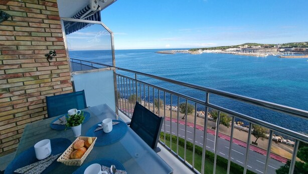 A balcony with a table set for breakfast, overlooking a coastal view with a clear sky and a distant shoreline. - Apartment in L'Escala near the beach, 2 bedrooms (L'Escala)