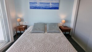 A bedroom with a large bed, two bedside tables, a painting of sailboats, and a window. - Apartment in L'Escala near the beach, 2 bedrooms (L'Escala)
