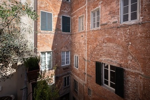 A multi-story brick building with multiple windows and a narrow alleyway.