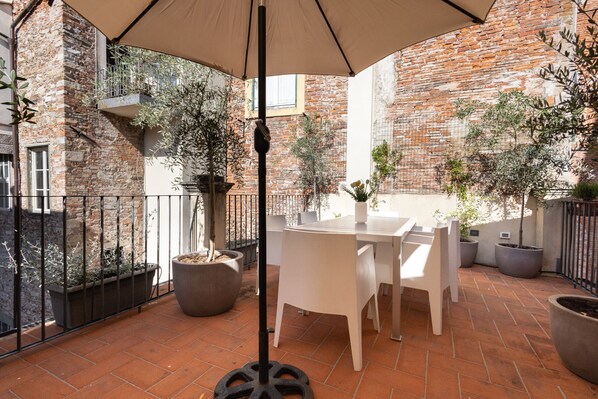 A patio with a table and chairs, surrounded by potted plants and a brick wall.