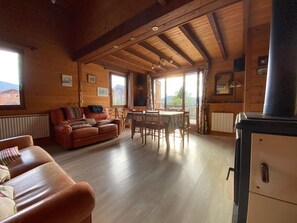 A cozy cabin interior with a wooden ceiling, a sofa, a dining table, and a fireplace. - Spacious 130 m² chalet in Crest-Voland with ski shuttle (Crest-Voland)