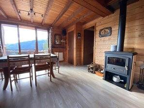 A wooden cabin interior with a dining area, a stove, and a view through the windows. - Spacious 130 m² chalet in Crest-Voland with ski shuttle (Crest-Voland)
