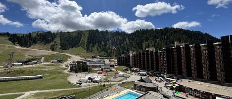 Ein Hotel mit Dachpool, eingebettet in eine gebirgige Landschaft unter wolkenlosem Himmel.