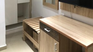 A bedroom with a wooden desk, a wardrobe, a mirror, and a TV mounted on the wall. - Davalon suites & Apartments (Lekki)