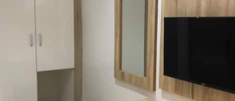 Ein modernes Badezimmer mit einem Holzwaschtisch, einem großen Spiegel und einem eingebauten Fernseher.