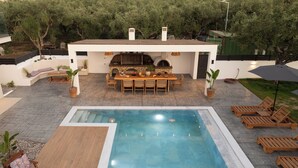 A pool area with a dining table and chairs, surrounded by potted plants and a barbecue grill. - The Olive Nest by Elite (Zakynthos)
