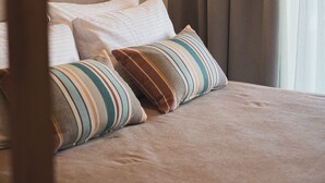 A neatly made bed with striped pillows, a headboard, and a hanging light fixture. - The Olive Nest by Elite (Zakynthos)