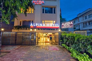 L’extérieur de l’hôtel Alpena, avec son entrée fermée par un portail, sa façade bien éclairée et son panneau indicateur.