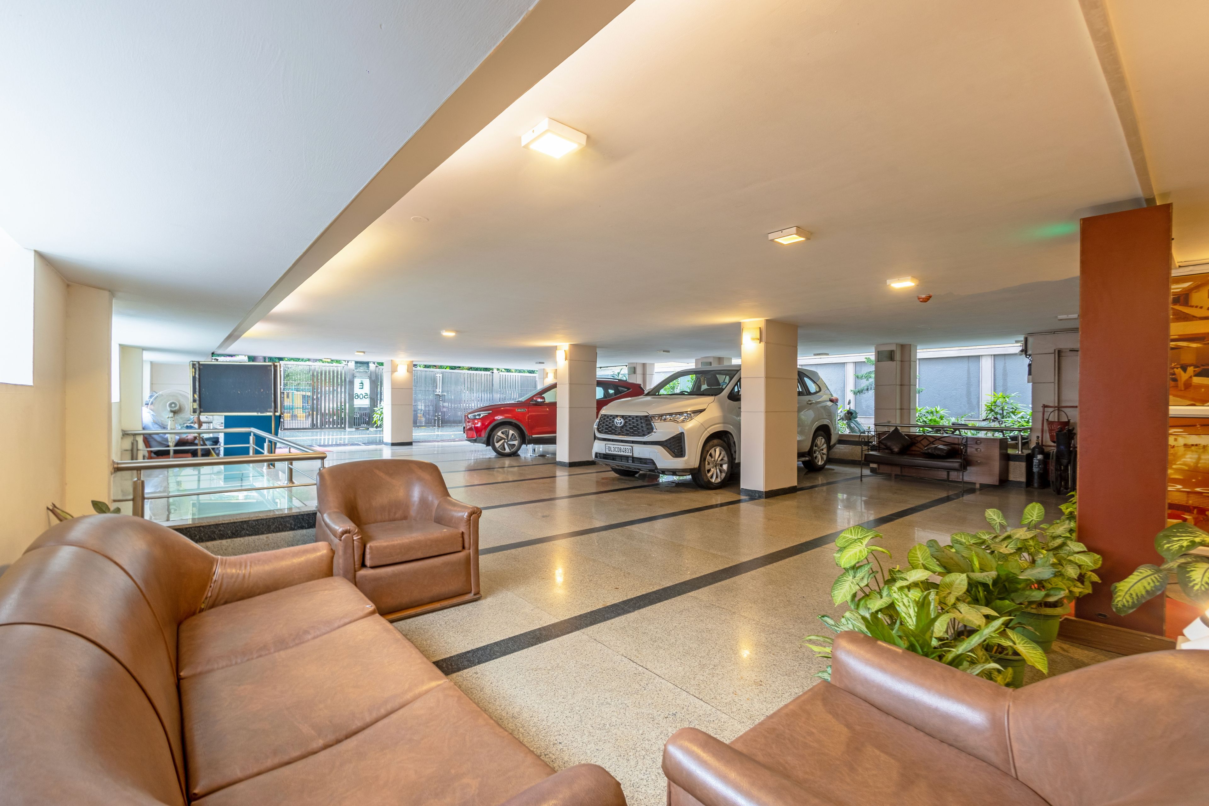 A spacious lobby with leather seating, a reception desk, and a parking area with cars.