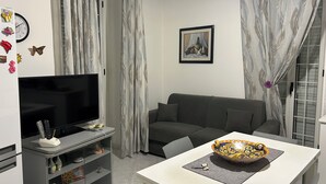 Ein Wohnzimmer mit Fernseher, Sofa und einem Tisch mit einer dekorativen Schale.