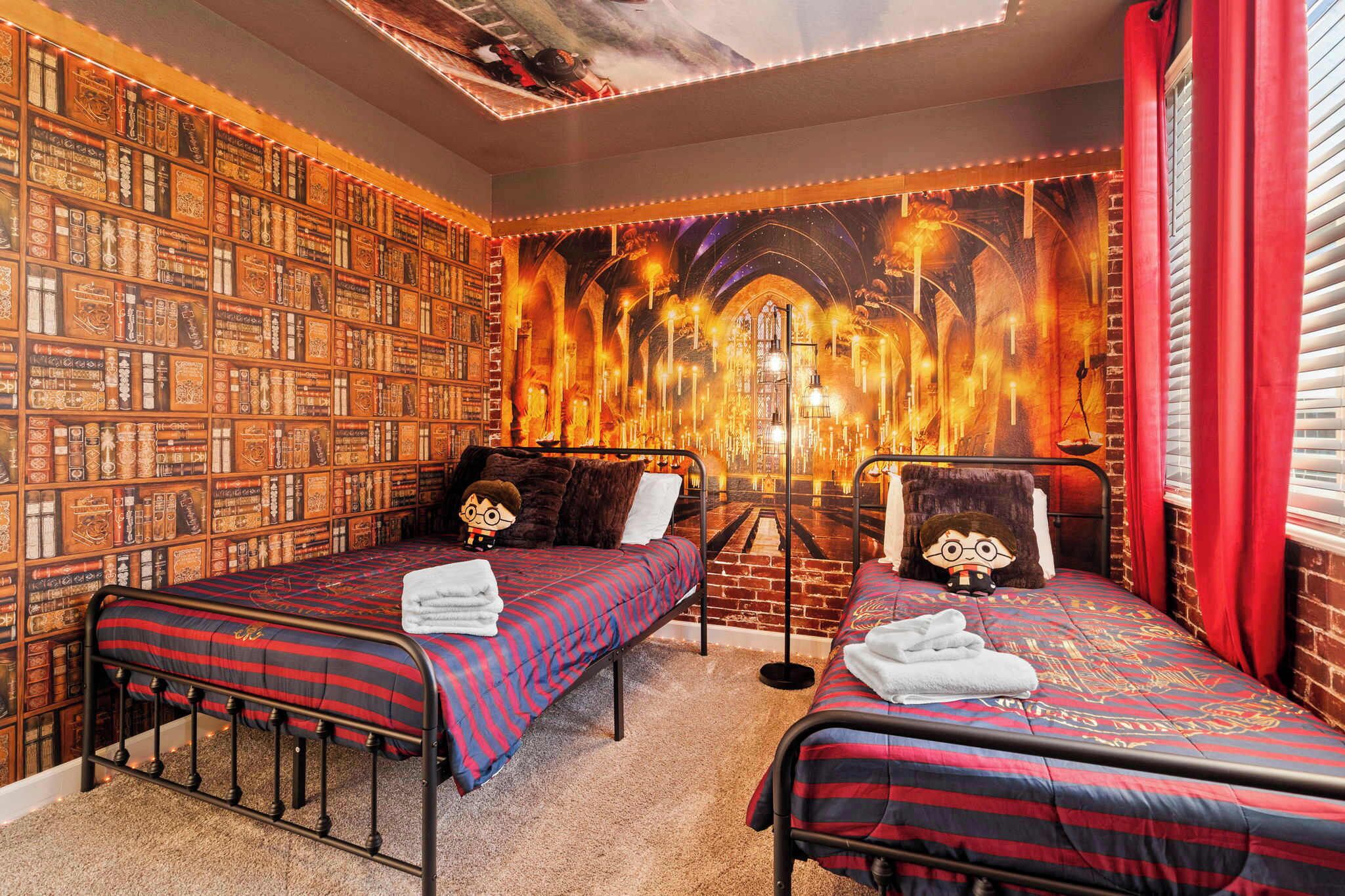 A room with two beds, a bookshelf, and a mural of a castle.