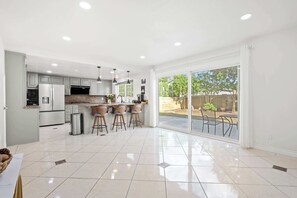A modern kitchen with a central island, bar stools, and a sliding glass door leading to a patio. - Cozy Full Suite Private Bathroom Quiet Stay (Norwalk)