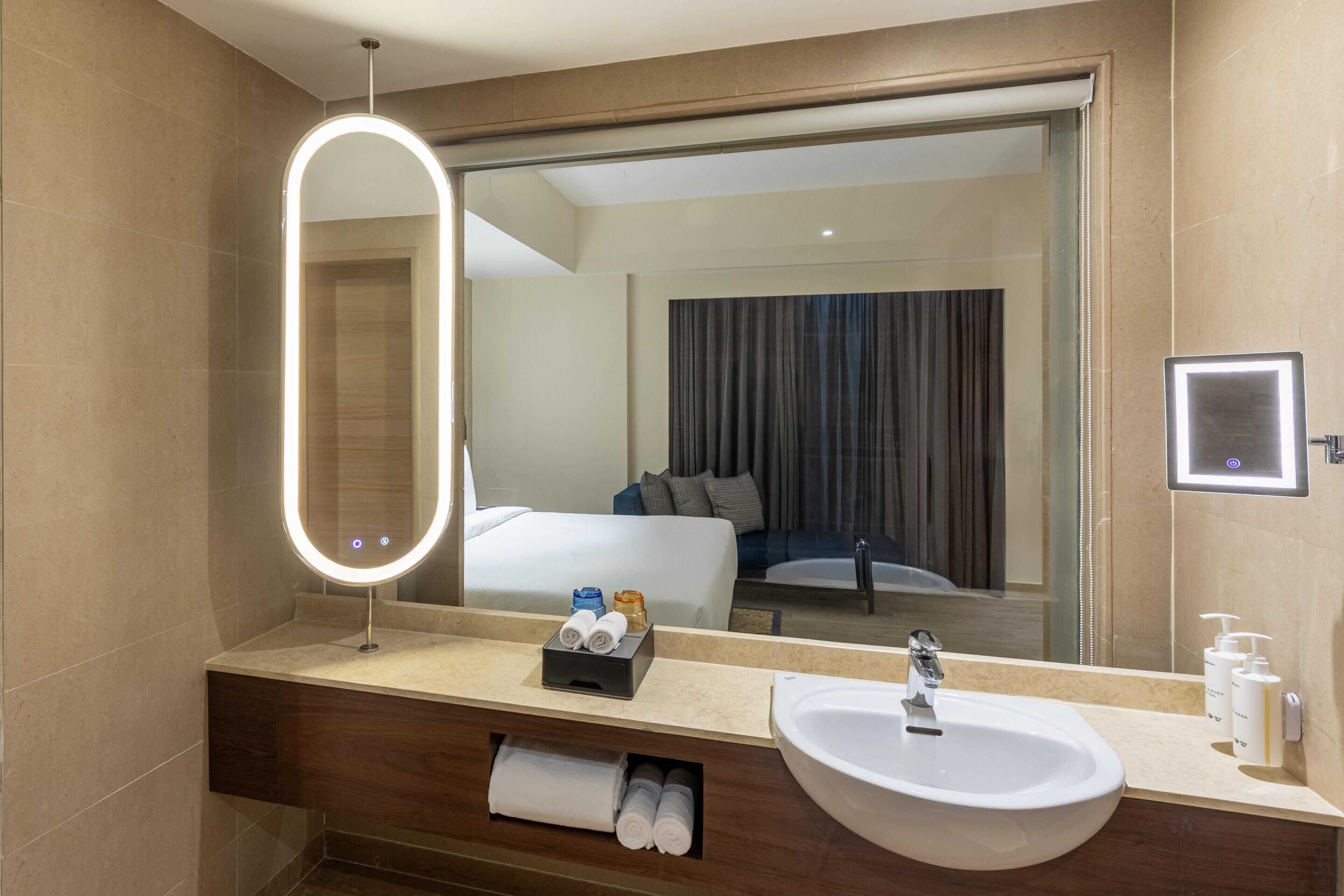 Un baño de hotel con un espejo grande, un lavabo y un perchero para toallas.