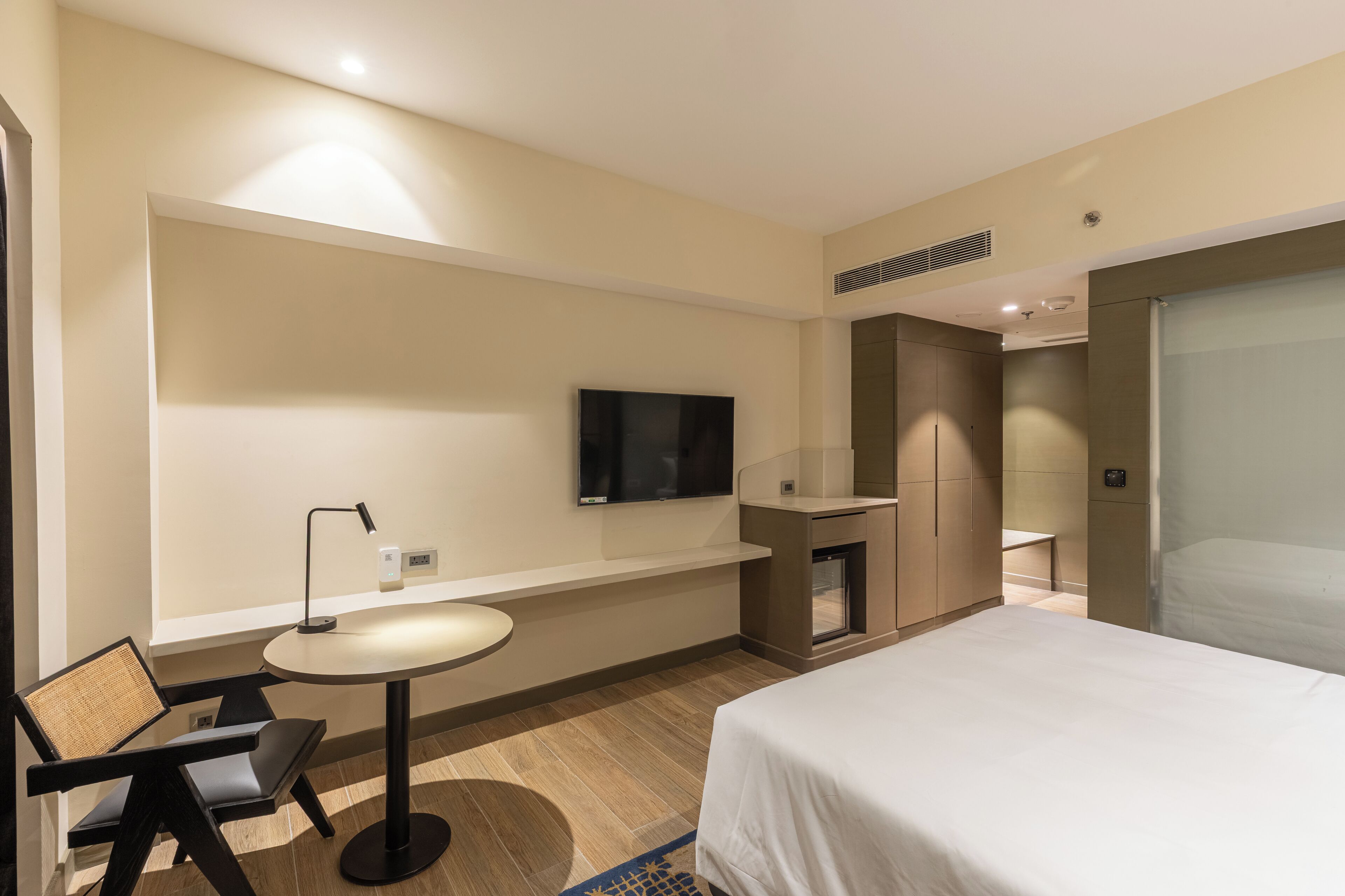 Une chambre d’hôtel comprenant un lit, un bureau avec une chaise, un téléviseur fixé au mur et un petit coin salon.