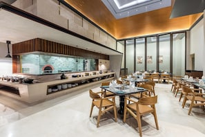 Un restaurante moderno con cocina central, sillas de madera y un diseño de interiores contemporáneo.