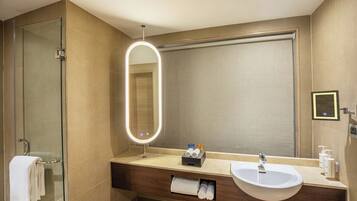 A modern bathroom with a glass shower, a vanity with a sink, and a large mirror.