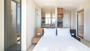 A modern hotel room with a large bed, a wooden headboard, a small bedside table, a built-in TV, and a sliding glass door leading to a balcony. - Eco Villa Mirada (Kalkan)