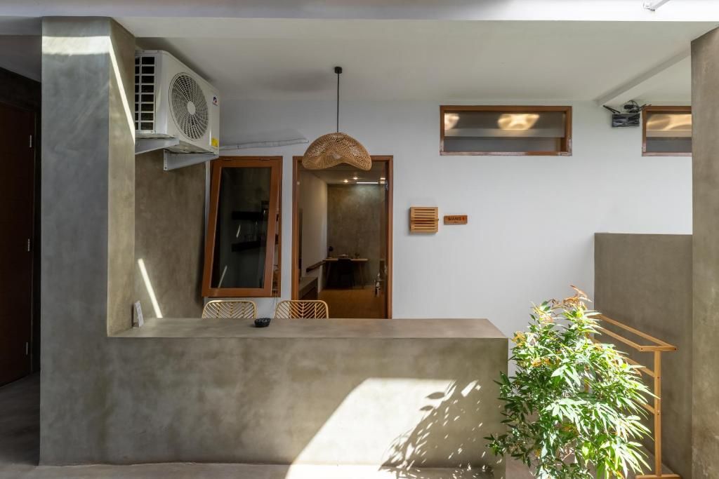 Interior moderno com balcão de recepção em concreto, luminária pendente e planta em vaso.