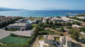 Un hôtel situé sur la côte, composé de plusieurs bâtiments, doté d’une piscine et offrant une vue sur la mer.