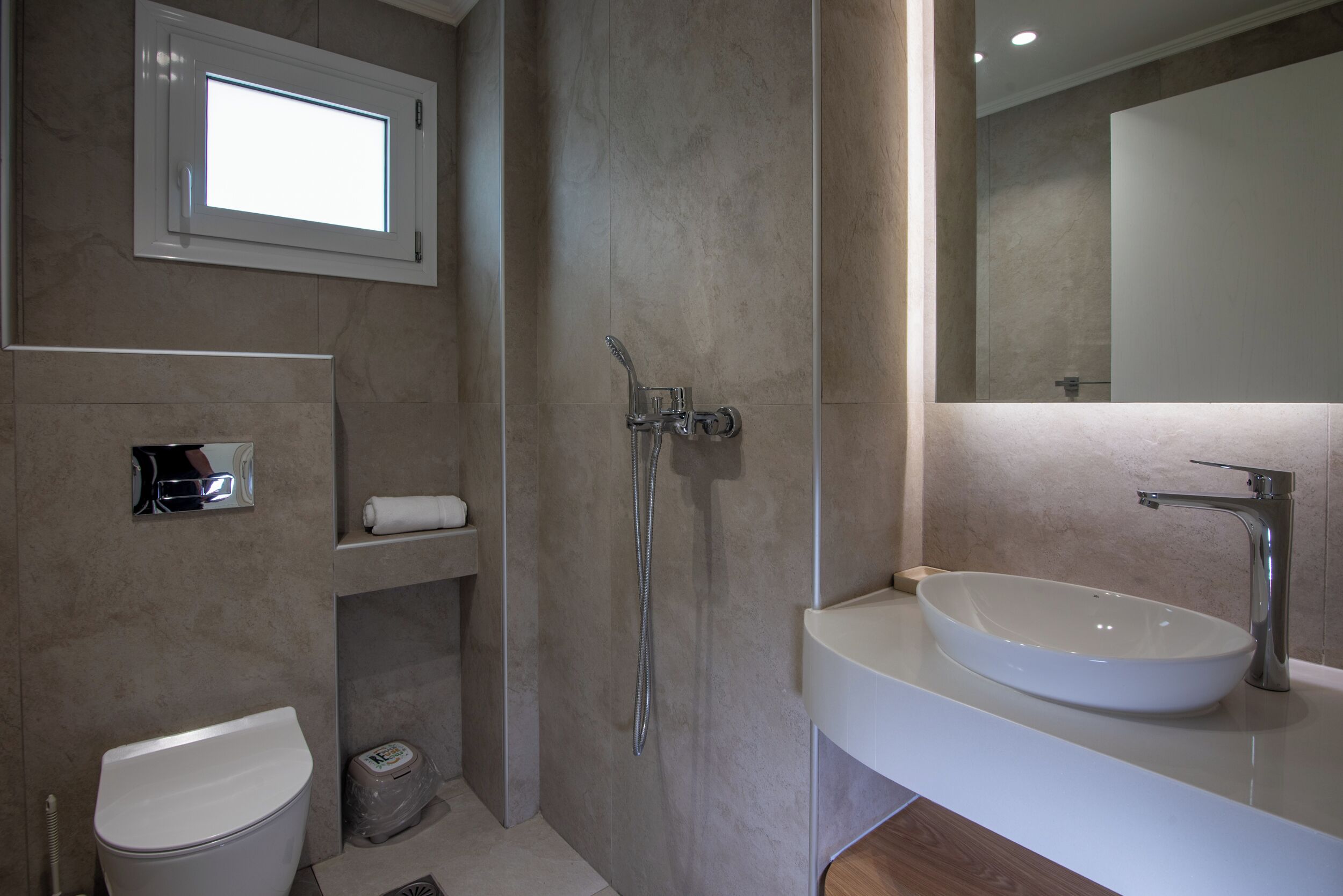 A modern bathroom with a white sink, a toilet, a shower, and a mirror.