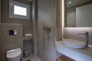 Une salle de bain moderne avec un lavabo blanc, des toilettes, une douche et un miroir.