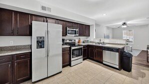 Una cocina moderna con armarios de madera oscura, electrodomésticos de acero inoxidable y encimera de granito.