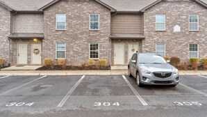 Filas de casas adosadas de ladrillo con espacios de estacionamiento numerados y un automóvil estacionado al frente.