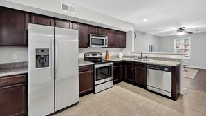 Una cocina moderna con armarios de madera oscura, electrodomésticos de acero inoxidable, encimeras de granito y lavavajillas integrado.