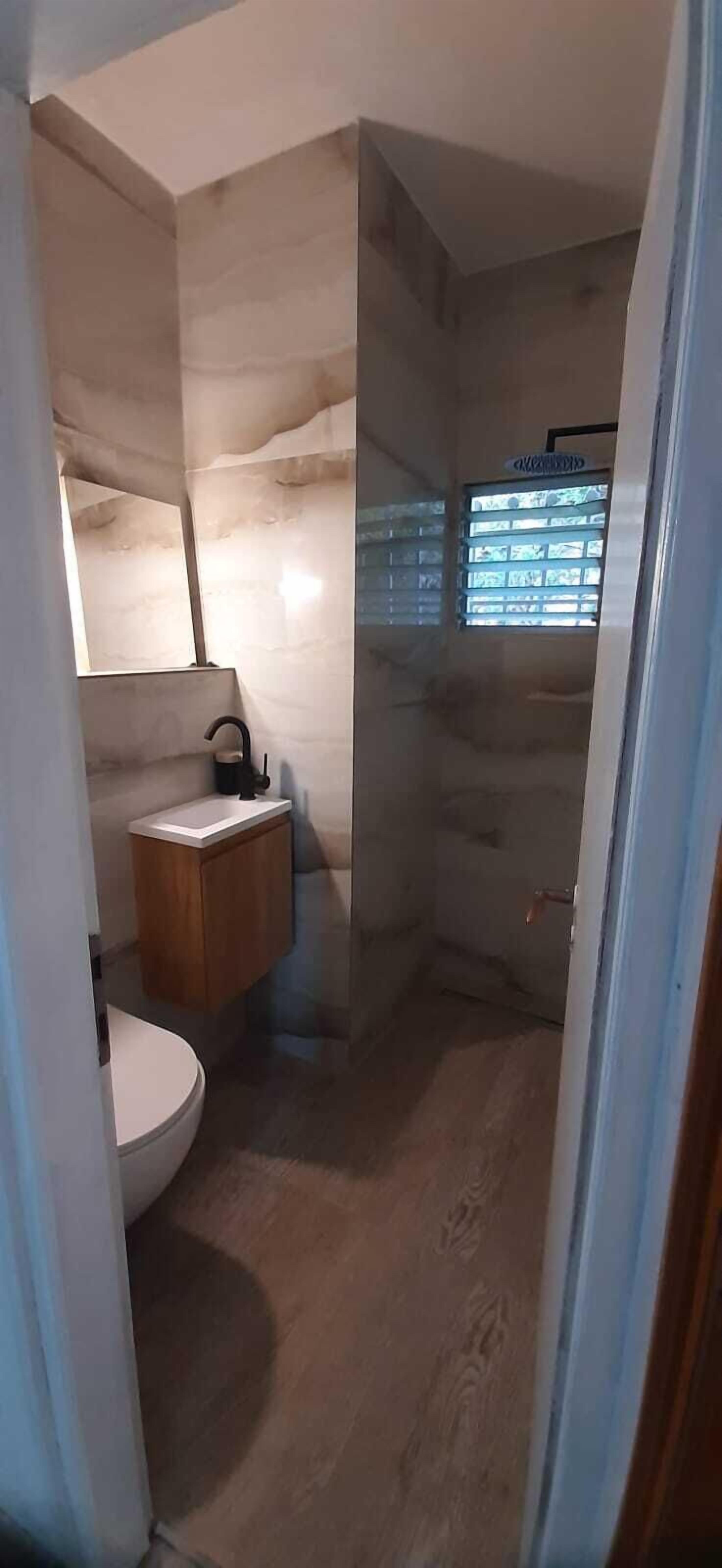 A bathroom with a toilet, sink, and shower area.