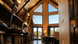 Una habitación amplia con techo alto, ventanas grandes y suelo de madera.