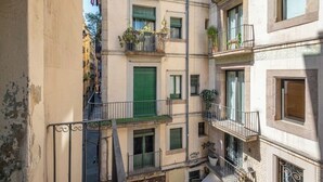 A multi-story building with balconies, a green door, and visible signage. - Cosy studio located in heart of Born (Barcelona)