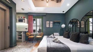 Een moderne hotelkamer met een groot bed, een bureau met stoel en uitzicht op de stad door een raam.