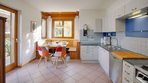A modern kitchen with white cabinets, a wooden countertop, and a dining area with a table and chairs. - Apartment Hofgarten - Alpstay (Naturno)