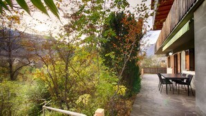 A patio with stone flooring, a wooden railing, and a table with chairs. - Apartment Hofgarten - Alpstay (Naturno)